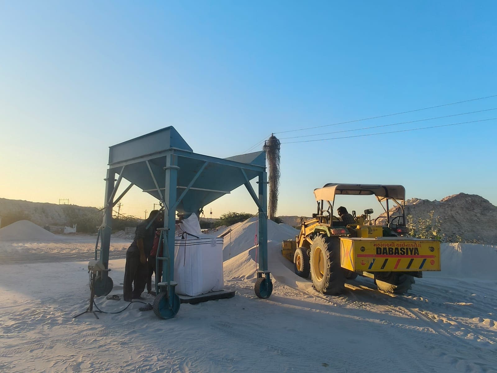 Jumbo bag filling station with hopper and loader at sunset