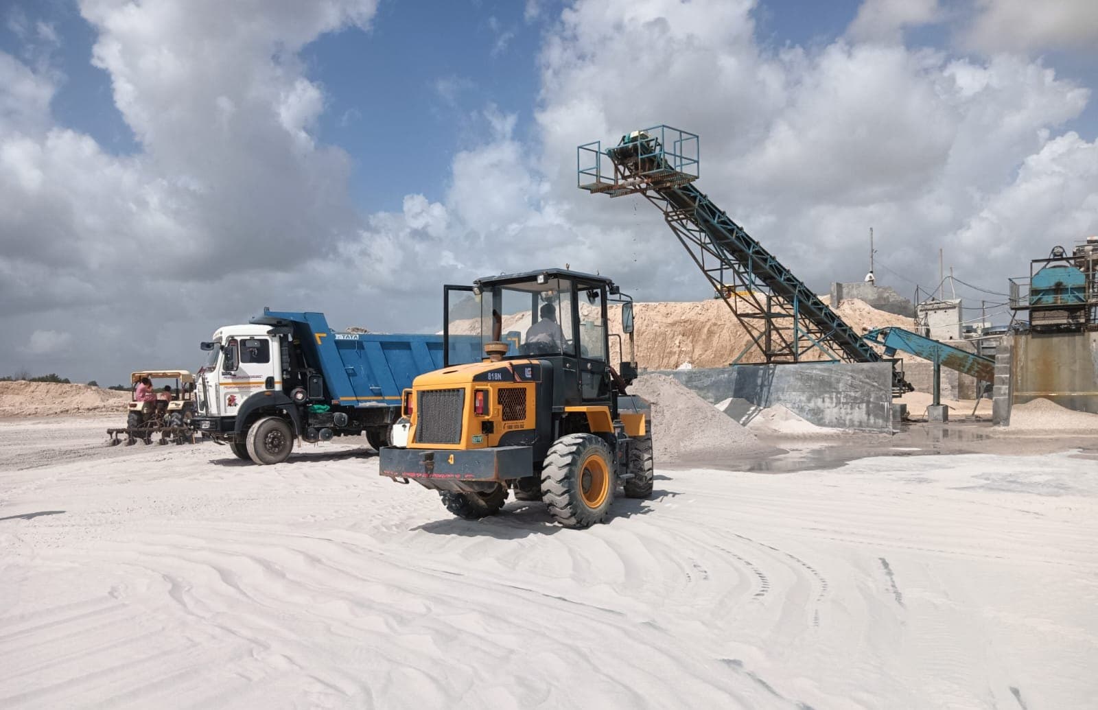 Wheel loader, truck and conveyor working in the white sand yard