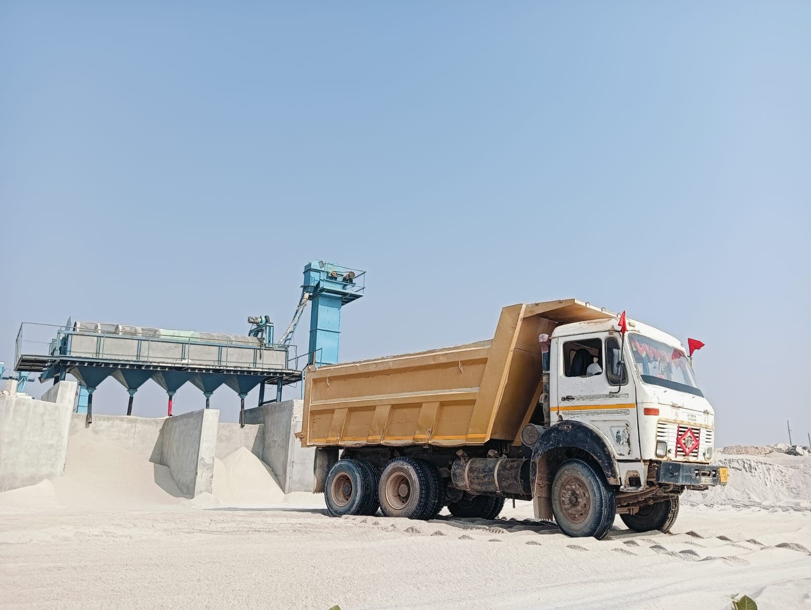 Tipper truck beside the hopper bins of the screening plant